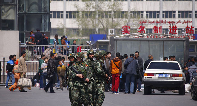 Paramilitary policemen stand guard near the exit of the South Railway Station in Urumqi