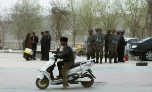Police officers check the identity cards of a people as security forces keep watch in a street in Kashgar